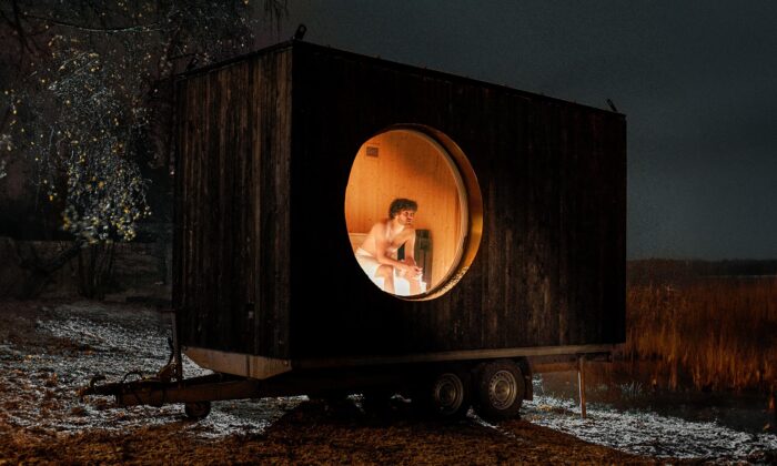 Sauna k světu je umístěna na kolech a má fasádu z černého opáleného dřeva s kulatým oknem